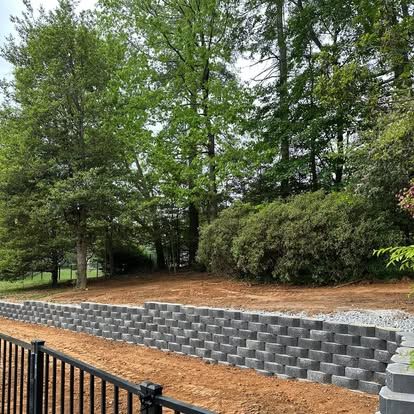 Block retaining wall along a freshly graded slope with trees behind