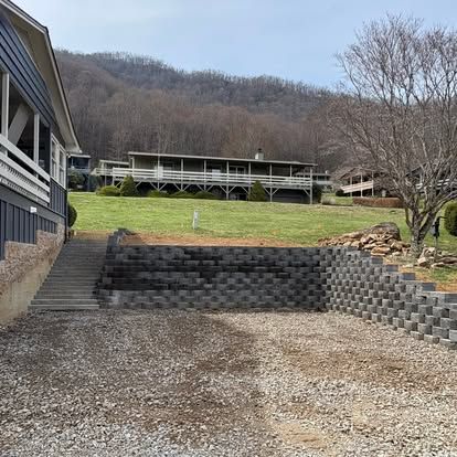 Gray block retaining wall with built-in steps beside a house